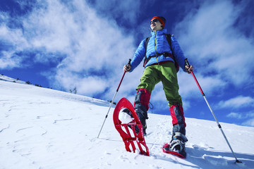 Winter hiking in the mountains on snowshoes with a backpack and tent.