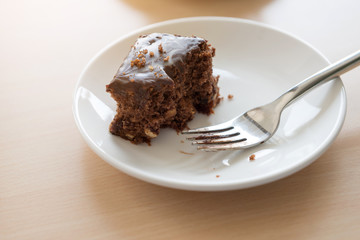 Brownie with fork in plate on wooden table. cut off