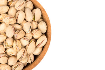 Part of a wooden bowl with pistachios on a white background, top view