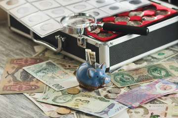 Coins and banknotes in the box, with a magnifying glass and piggy bank