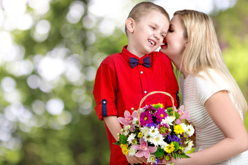  Young beautiful mother with her son.To whisper a secret in your ear.       Woman and child with bouquet of flowers. Spring family holiday concept. Women's day.