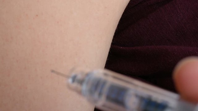 Macro of giving an intramuscular anticoagulant injection into the arm using a safety syringe.
