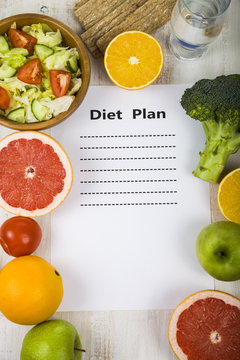 Food and sheet of paper with a diet plan on a  wooden table.