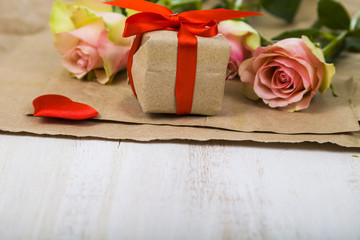 Pink roses,  gift and hearts on a wooden background.