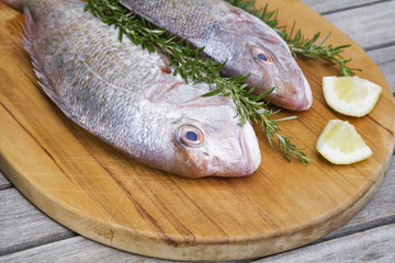 Red snapper with rosemary and lemon on chopping board