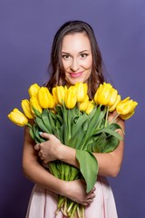 Young beautiful woman holding a bouquet of yellow tulips. Spring.