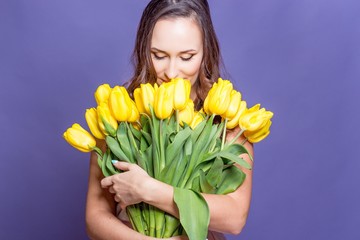 Young beautiful woman holding a bouquet of yellow tulips. Spring.