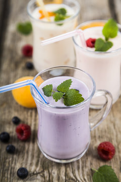 Smoothies or yogurt with fresh berries on a wooden table.