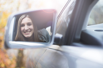 Young woman smiling in car mirror