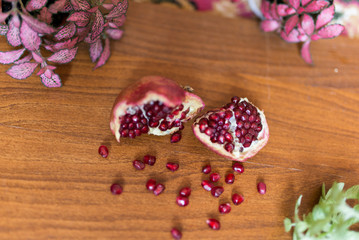 Fresh ripe pomegranate on a wooden table with green leafs