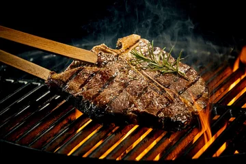 Poster Grilling a tasty tender t-bone steak on the fire © exclusive-design