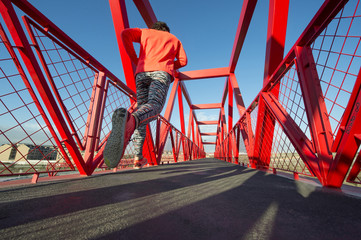 Young man running on the red bridge