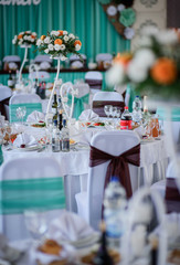 Chairs twined with brown cloth stand around dinner tables ready for wedding party