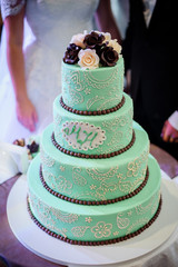 Green tired wedding cake decorated with chocolate balls and newlyweds initials