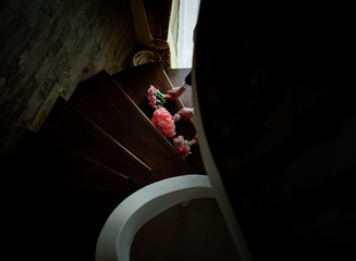 Men take pink wedding bouquets from wooden spiral stairs