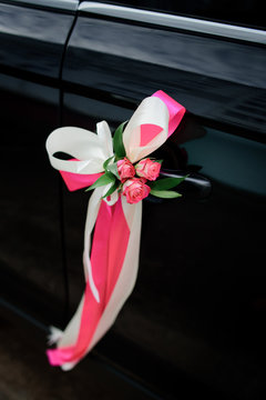 Pink roses twined with pink ribbon around car door handle