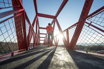 Young man running on the red bridge