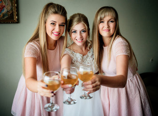 Bride and bridesmaids in pink dresses hold glasses with apple juice