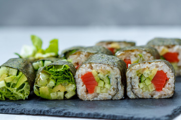 Healthy homemade sushi rolls with brown rice, fish and green vegetable rolls.