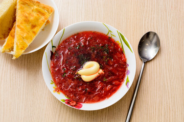 Borsch in a bowl with seasonings on a table