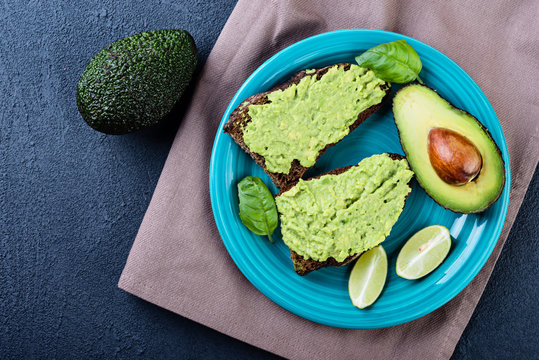 Avocado spread. Fresh sliced avocado and guacamole on dark background