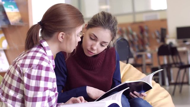 Two girls studying scientific books in library