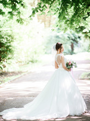 Fototapeta na wymiar White light illuminates gorgeous bride posing on pass in park