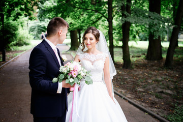 Happy newlyweds walk along the path in park