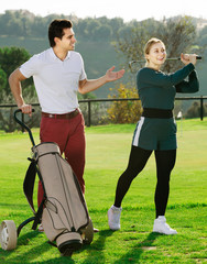 Fototapeta premium Man 30-35 years old is showing woman 25-29 years old to play golf