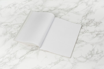 Mock-up magazine or catalog on white marble table. Blank page or notepad on stone background. Blank page or notepad for mockups or simulations.