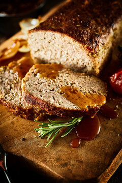 Sliced Meatloaf On Wood Board With Herbs And Gravy