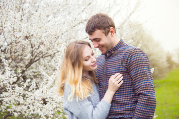 Fototapeta premium Young romantic couple standing in front of wonderful blooming trees in spring garden