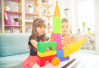 Siblings playing with colorful blocks at home, happy family