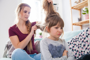 Mother has problem with combing hair of unhappy daughter