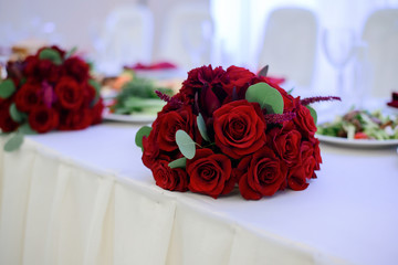 Little bouquets of red roses lie on white dinner table