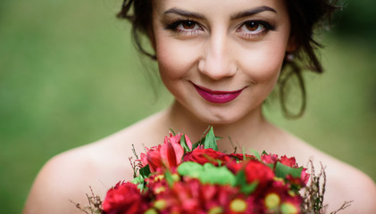 Fototapeta premium Bride with shiny dark hair holds red wedding bouquet