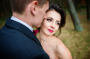 Tender touches of wedding couple hugging in the forest