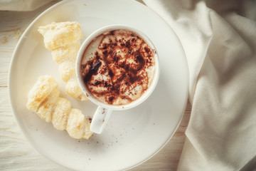 Cup of hot cocoa and cream cakes