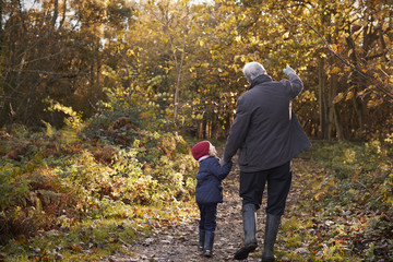 Obraz premium Grandfather And Granddaughter Enjoying Autumn Walk
