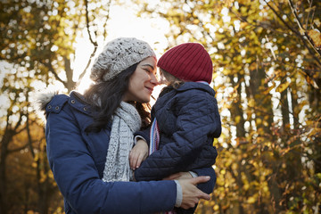 Mother Cuddling Daughter On Walk In Autumn Countryside