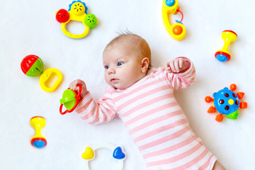 Fototapeta na wymiar Cute baby girl playing with colorful rattle toys