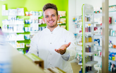 Naklejka na ściany i meble Laughing pharmacist standing among shelves