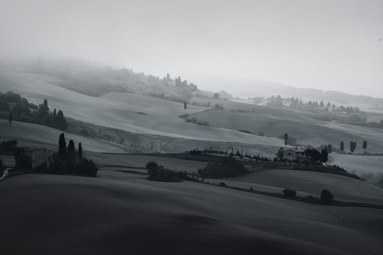 Black and white beautiful summer morning landscape with foggy hills and Tuscany farm houses, travel italian background