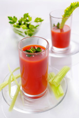 Tomato juice in glasses with parsley and celery. Fresh juice of tomato.