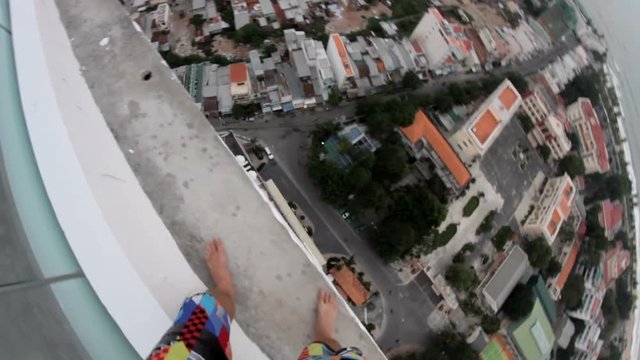 Man standing on the edge of a tall building and shoots