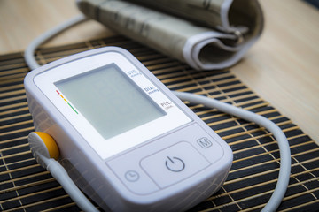 Digital blood pressure meter on wooden table with blank monitor