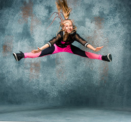 Fototapeta na wymiar Young girl break dancing on wall background.