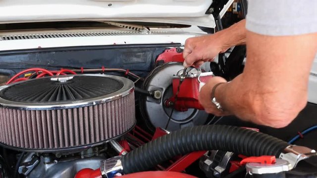 A man checking the oil level on his classic car