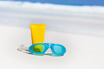 Sun screen lotion and swimming glasses on beach