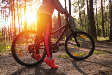 Fototapeta premium Woman riding a mountain bicycle along path at the forest